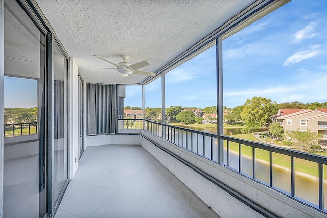 unfurnished sunroom with ceiling fan and a water view