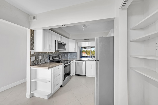 kitchen with white cabinets, decorative backsplash, stainless steel appliances, and light tile patterned floors