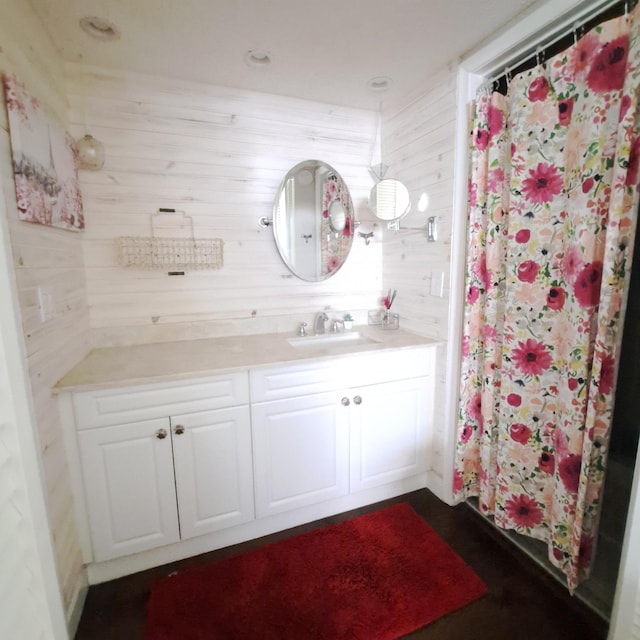 bathroom with a shower with shower curtain, vanity, and wooden walls