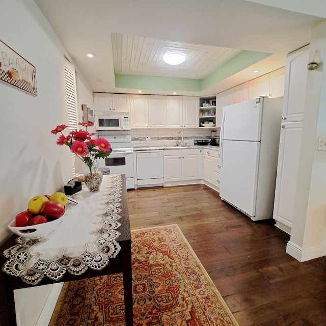 kitchen featuring a tray ceiling, white cabinetry, white appliances, and hardwood / wood-style flooring