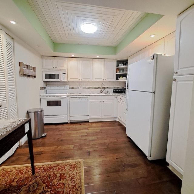 kitchen with white appliances, backsplash, white cabinets, a raised ceiling, and dark hardwood / wood-style flooring