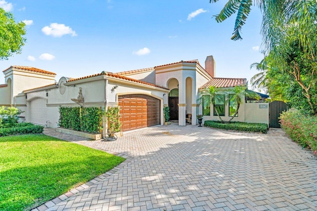 mediterranean / spanish house featuring a garage and a front yard