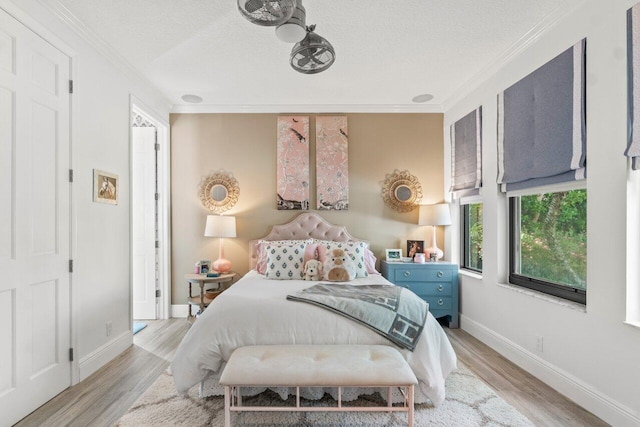 bedroom featuring a textured ceiling, crown molding, and light hardwood / wood-style flooring