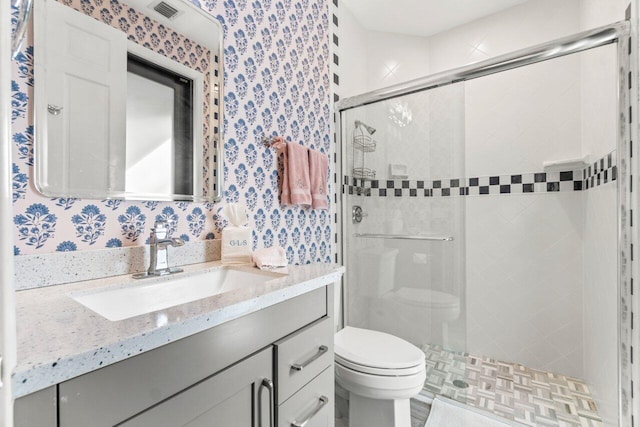 bathroom with vanity, toilet, and a shower with door