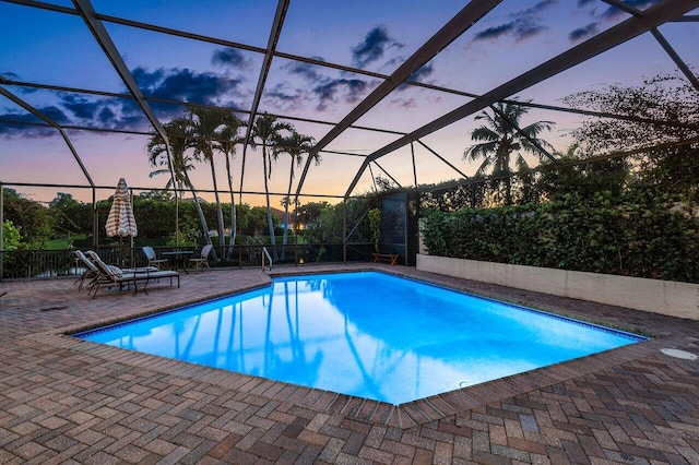 pool at dusk featuring a patio area and a lanai