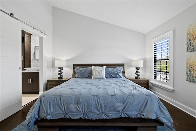 bedroom with hardwood / wood-style flooring, ensuite bathroom, and lofted ceiling