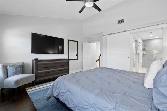 bedroom featuring connected bathroom, a barn door, ceiling fan, and light wood-type flooring