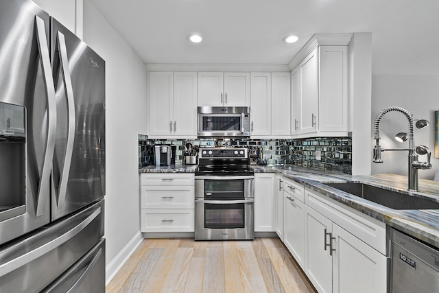 kitchen with dark stone countertops, sink, white cabinets, and stainless steel appliances