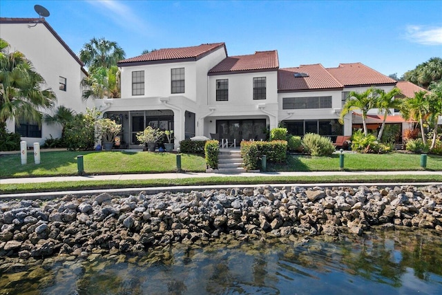 rear view of property with a yard and a water view