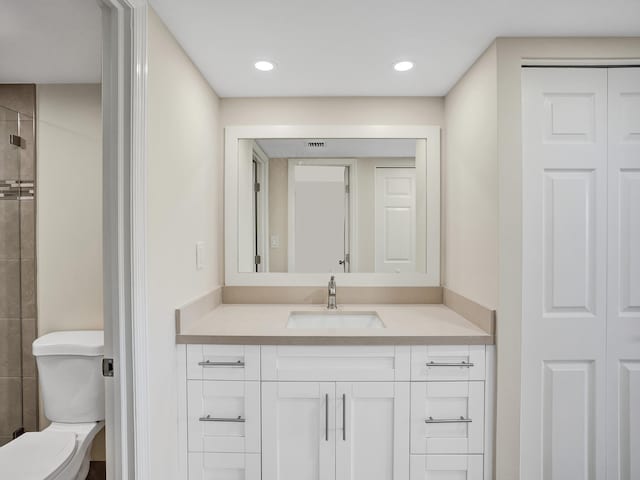 bathroom with vanity, toilet, and tiled shower