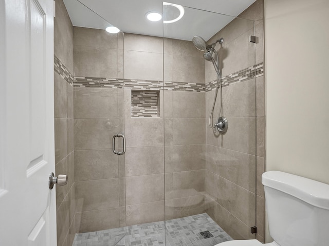 bathroom featuring a shower with shower door and toilet