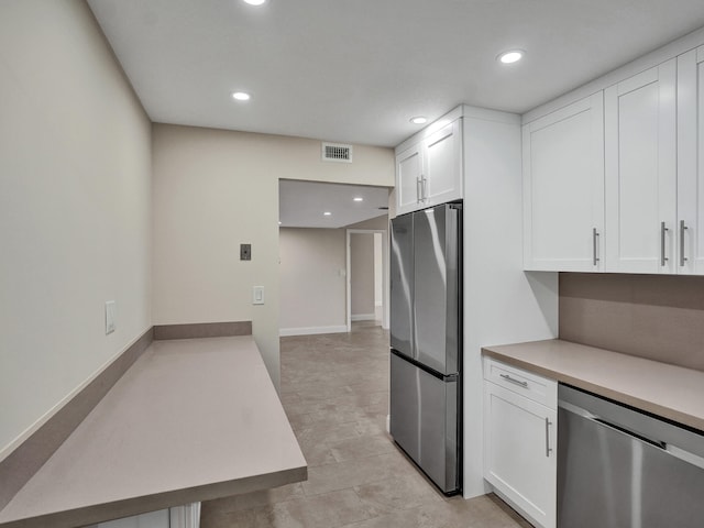 kitchen featuring kitchen peninsula, appliances with stainless steel finishes, and white cabinetry