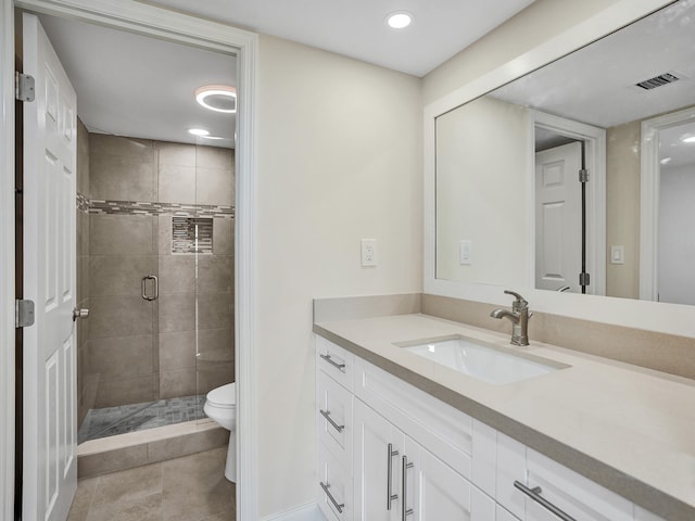 bathroom featuring tile patterned flooring, vanity, toilet, and a shower with door