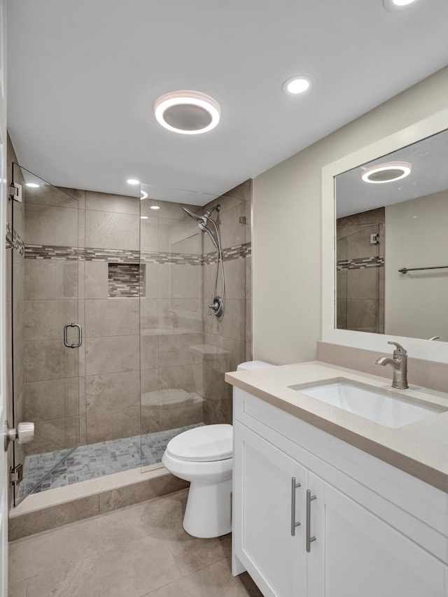 bathroom with tile patterned floors, vanity, toilet, and a shower with door