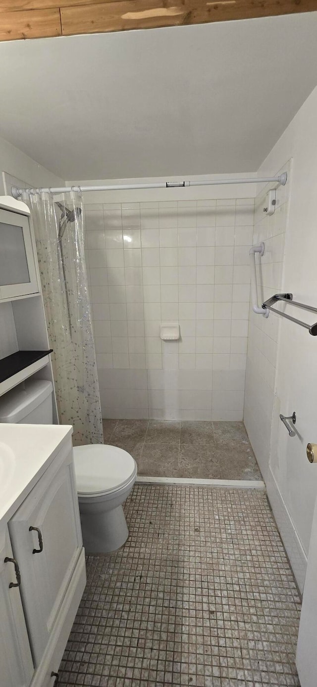 bathroom with tile patterned floors, toilet, vanity, and walk in shower