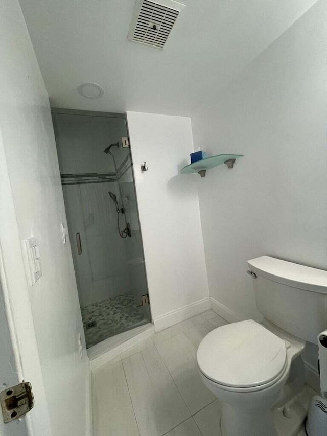 bathroom featuring a shower with door, tile patterned flooring, and toilet