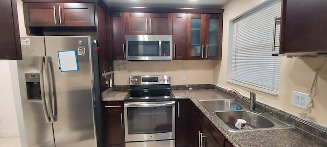 kitchen with stainless steel appliances, dark stone counters, and sink