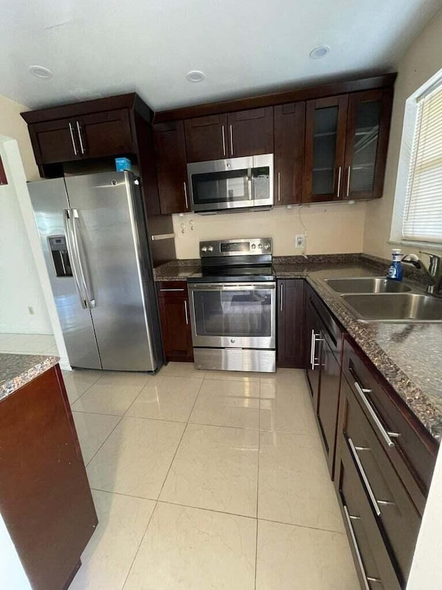 kitchen with light tile patterned flooring, sink, dark brown cabinetry, and stainless steel appliances