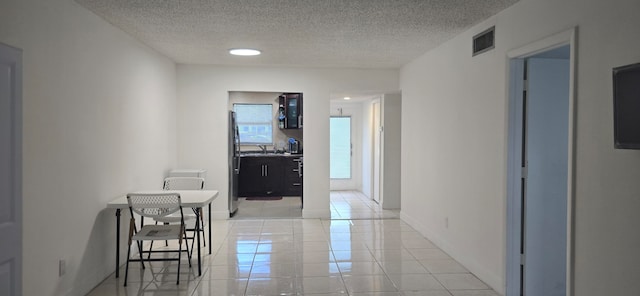 hallway featuring light tile patterned flooring and a textured ceiling