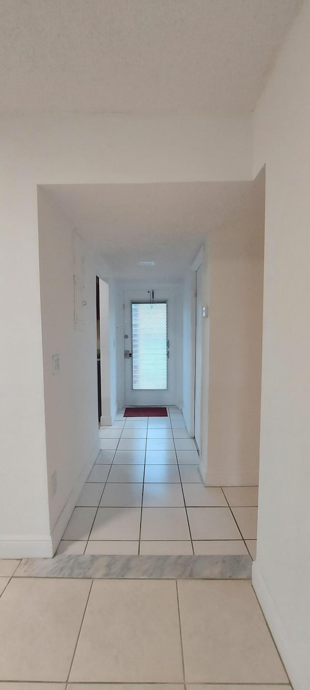 corridor featuring light tile patterned floors and a textured ceiling