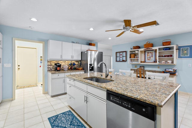 kitchen with appliances with stainless steel finishes, sink, light tile patterned floors, a center island with sink, and white cabinets