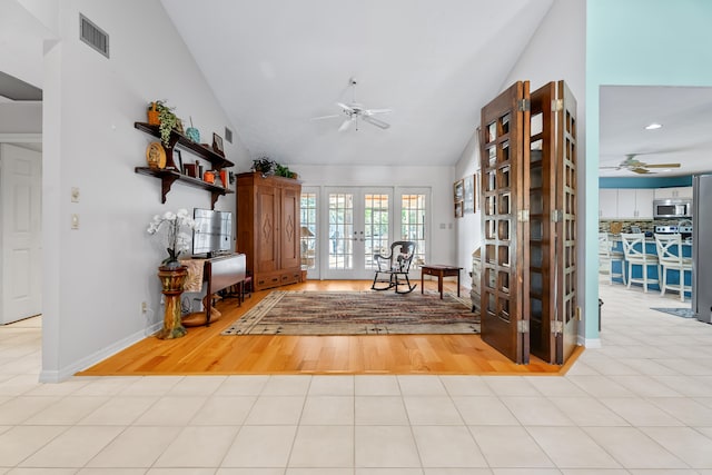 unfurnished room with ceiling fan, light wood-type flooring, high vaulted ceiling, and french doors