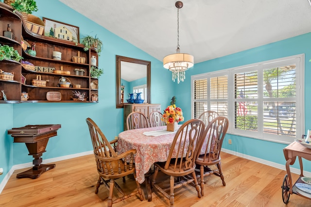 dining room with an inviting chandelier, light wood-type flooring, and vaulted ceiling