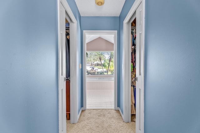 corridor featuring a textured ceiling, light carpet, and lofted ceiling