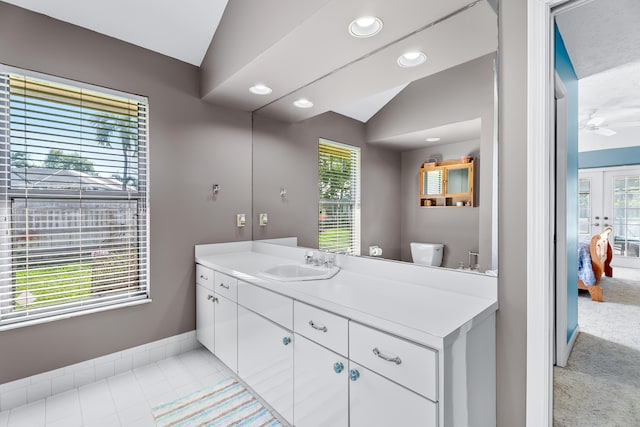 bathroom with tile patterned floors, vanity, vaulted ceiling, and toilet