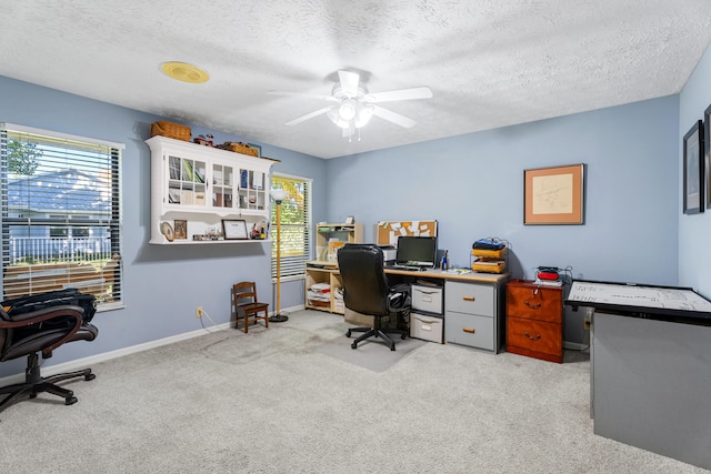 office area featuring light carpet, ceiling fan, and a textured ceiling