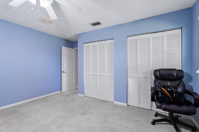 carpeted office space with a textured ceiling and ceiling fan