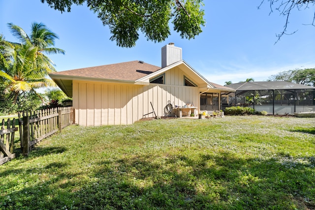 back of house with glass enclosure and a lawn