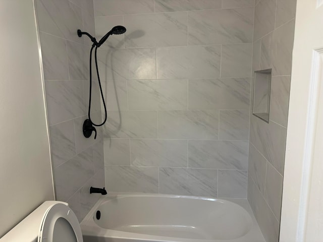 bathroom featuring tiled shower / bath combo and toilet