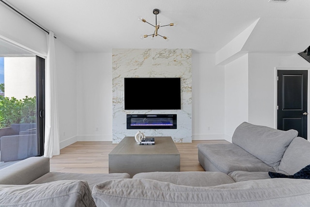 living room featuring a premium fireplace, a chandelier, and light wood-type flooring