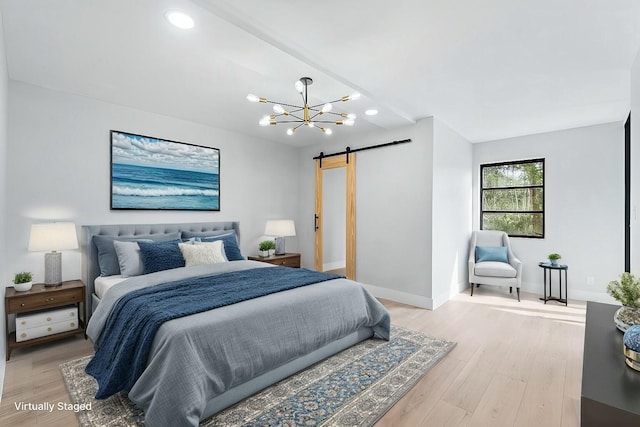 bedroom featuring light wood finished floors, a barn door, baseboards, and an inviting chandelier