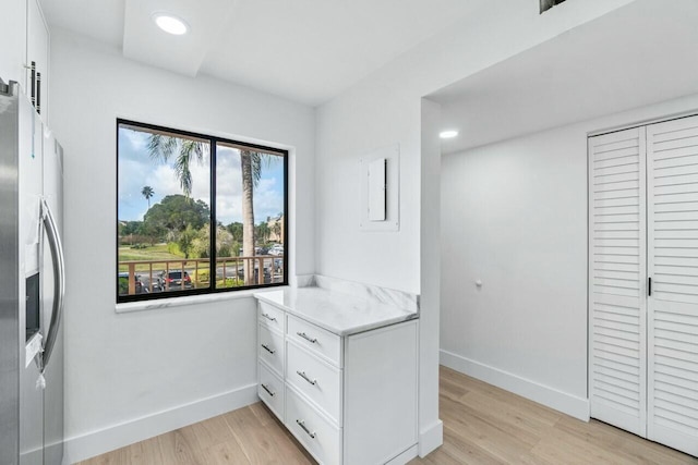 interior space with white cabinets, light hardwood / wood-style floors, and stainless steel fridge with ice dispenser