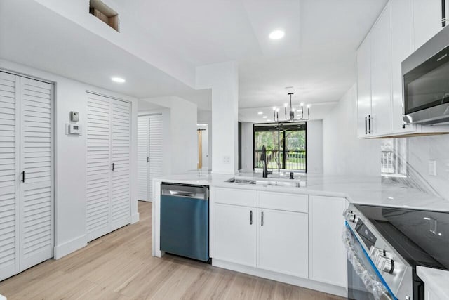 kitchen with sink, light hardwood / wood-style flooring, appliances with stainless steel finishes, white cabinetry, and kitchen peninsula