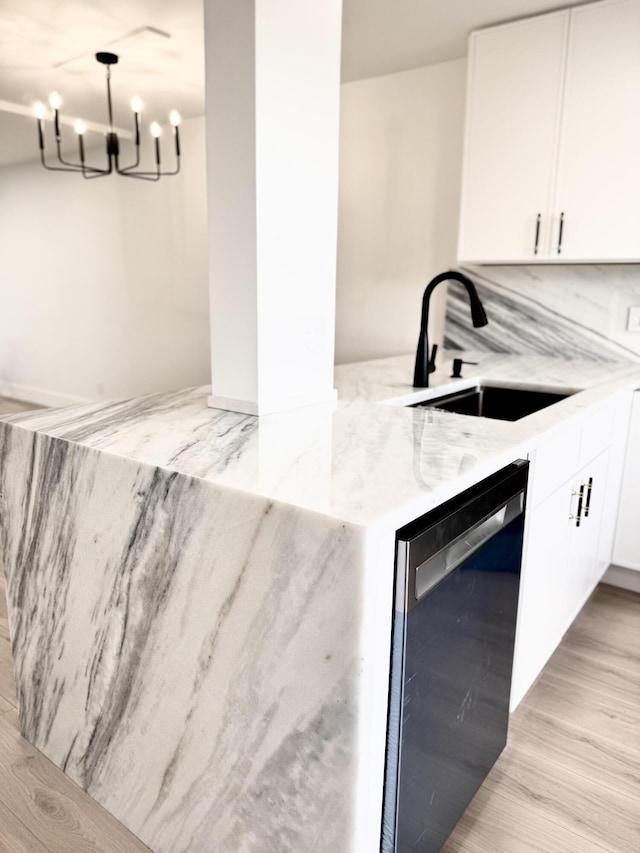 interior space with dishwashing machine, sink, light stone countertops, white cabinets, and light wood-type flooring