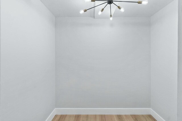 empty room with a notable chandelier, light hardwood / wood-style flooring, and a barn door