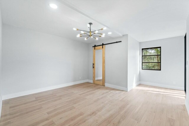 bedroom with an inviting chandelier, hardwood / wood-style floors, and a barn door