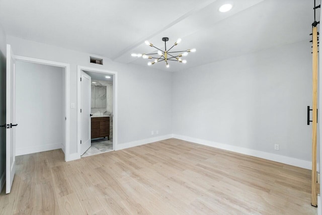 spare room with a notable chandelier and light wood-type flooring