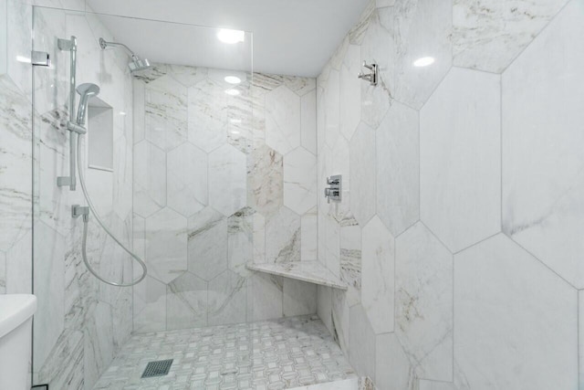 bathroom featuring a tile shower and toilet