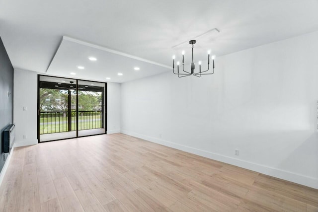 interior space with expansive windows, heating unit, an inviting chandelier, and light hardwood / wood-style floors