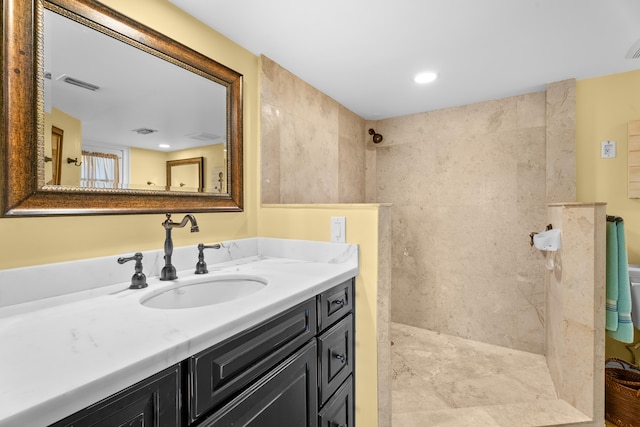 bathroom with a tile shower and vanity