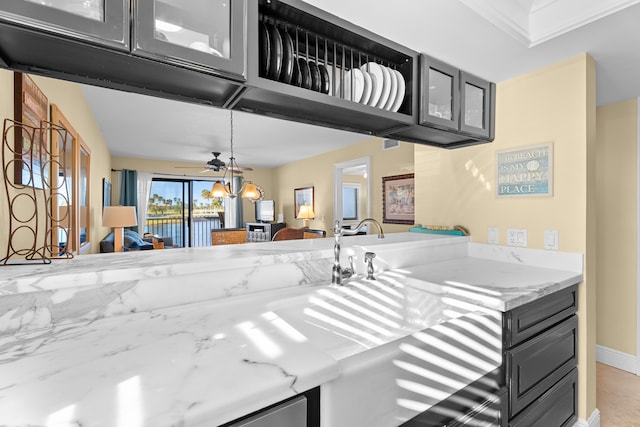 kitchen featuring ceiling fan and light stone countertops