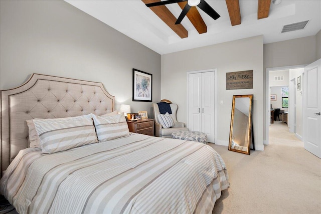 bedroom with beam ceiling, ceiling fan, a closet, and light carpet