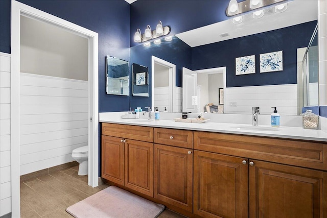 bathroom with vanity, toilet, and wood walls