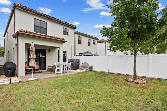 rear view of house featuring a lawn and a patio