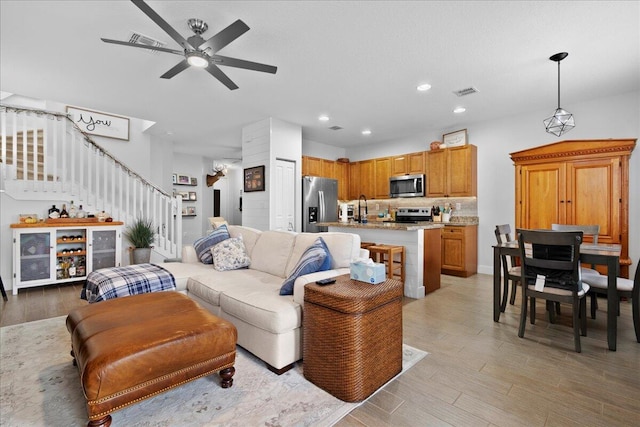 living room with light hardwood / wood-style flooring, ceiling fan, and sink