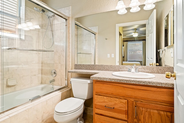 full bathroom with ceiling fan, vanity, bath / shower combo with glass door, and toilet